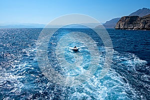 Motor boat sailing into the sea behind the ship in the sea foam