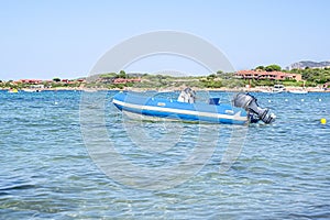 Motor boat in the sea against the coast with houses, mountains in Sardinia, Italy