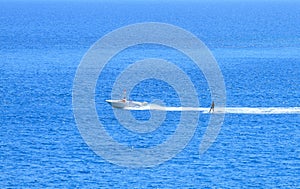 Motor boat and surfer on the blue sea