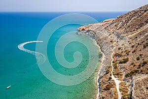 Motor boats leaving trail in Pissouri bay, Cyprus with Mediterranean sea on background, aerial seascape