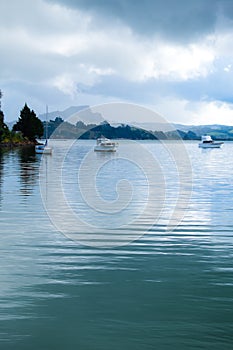 Motor boats and a sailing yacht anchored in Whangaroa Harbour, F
