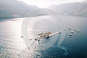 Motor boats and ships stand around the island of Gospa od Skrpjela. Montenegro. Drone