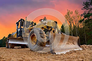 Motor Grader on road construction in forest area. Greyder leveling the sand, ground and gravel during road work. Heavy machinery