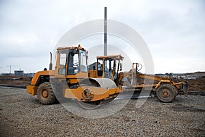 Motor Grader and Soil Compactor at a construction site level the ground and gravel stones for the construction of a new asphalt