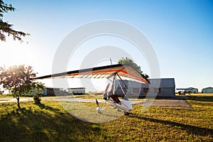 Motor hang glider standing on green grass at aerodrome, bright summer day