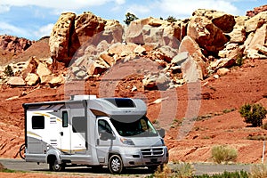 Motor home RV traveling through red rocks in Utah.