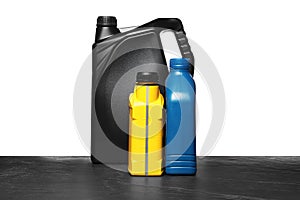 Motor oil in different canisters on black table against white background