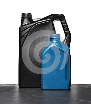 Motor oil in different canisters on black table against white background