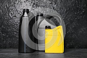 Motor oil in different canisters on black table near dark wall