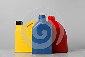 Motor oil in different canisters on grey marble table against light background