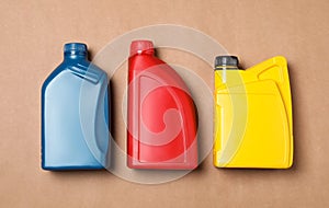 Motor oil in different canisters on light brown background, flat lay