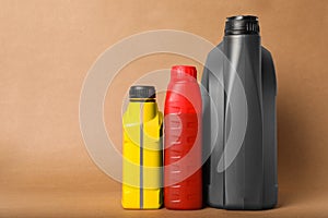 Motor oil in different canisters on light brown background, space for text