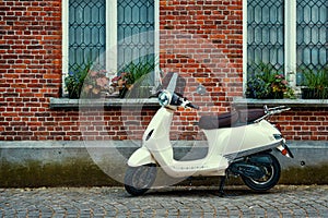 Motor scooter motorcycle parked near the wall of an old house