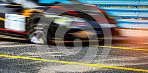 Motor sport car racing on asphalt road with blue fence and yellow line traffic sign. Car with fast speed driving and motion