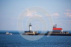 Motor yacht passing by the lighthouse on North Pier in Duluth Harbor