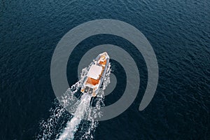 Motor yacht sails on the sea leaving a white foamy trail. Drone
