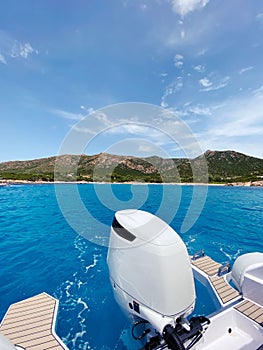 Motor yachtsailing across a tranquil blue ocean, with a lush green hill in the background