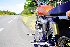 Motorbike alone aside route is vintage orange motorcycle parked in road in summer day