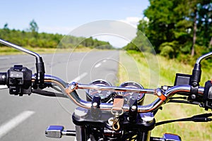 Motorbike chrome handlebars of classic vintage motorcycle parked in a road in summer countryside