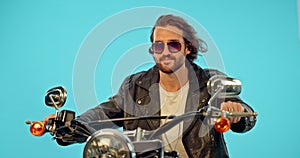 Motorbike, fashion and man riding in studio isolated on blue background with road trip, travel and biker aesthetic