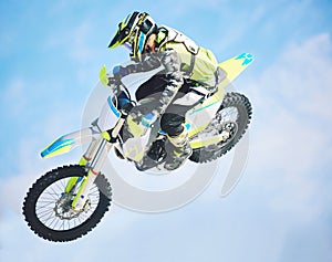 Motorbike, jump and man in the air with blue sky, mock up and stunt in sports with fearless person in danger with