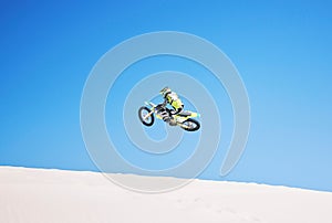 Motorbike, jump and man in the air with blue sky, mock up and stunt in sports with fearless person in danger with