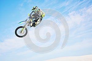 Motorbike, jump and person in the air with blue sky, mock up and stunt in sports with fearless person in danger with