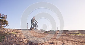Motorbike, jump and person in off road sport in desert, sand with path on hill for stunt challenge. Dirt, trail and