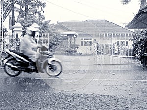 A motorbike rider passes through a rainy road photo