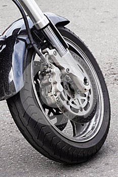Motorbike wheel. Close-up of the front wheel of a motorcycle and brake disc. Chrome fork and black motorbike wing