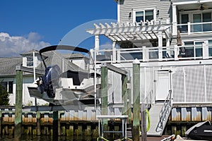Motorboat on a boat lift out of the water near a dock behind a house