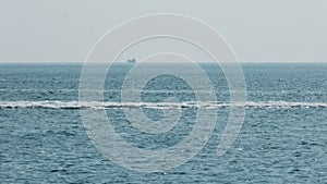 Motorboat cruising on blue sea with splashing water, clear sky in the background