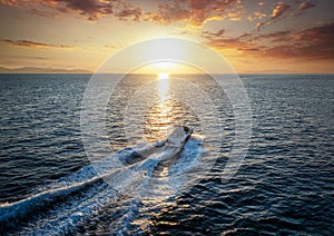 A motorboat cruising over the sea into the sunset