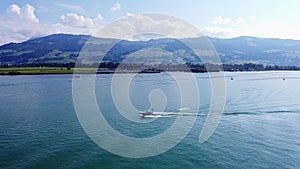 Motorboat driving straight line on Lake Zurich, Switzerland. Watersport and drone aerial shot back view