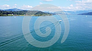 Motorboat driving straight line on Lake Zurich, Switzerland. Watersport and drone aerial shot back view