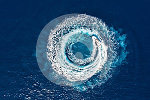 Motorboat forms a circle of waves and bubbles with its engines