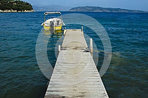 Motorboat moored to a wooden pier on the bottom there are islands in the sea there is none