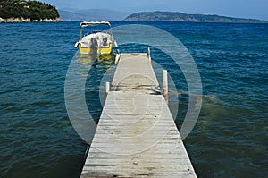 Motorboat moored to a wooden pier on the bottom there are islands in the sea there is none photo