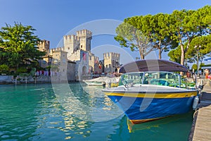 Motorboat at port Sirmione in front of castello Scaligero at lake Garda