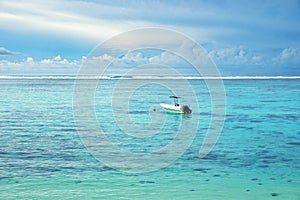 Motorboat sailing towards the horizon in the blue sea against the cloudy blue sky