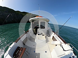 Motorboat in the sea with fishing rods and captain on the board and Beautiful island in background.