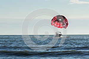 Motorboat towing a parasail parachute with a suspended person in