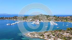 Motorboats and sailboats anchored in harbor with amazing blue sea on sunny summer day. Aerial view