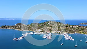 Motorboats and sailboats anchored in harbor with amazing blue sea on sunny summer day. Aerial view