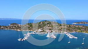 Motorboats and sailboats anchored in harbor with amazing blue sea on sunny summer day. Aerial view