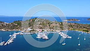 Motorboats and sailboats anchored in harbor with amazing blue sea on sunny summer day. Aerial view