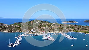 Motorboats and sailboats anchored in harbor with amazing blue sea on sunny summer day. Aerial view