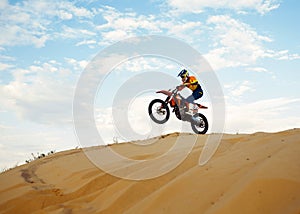 Motorcross riding over sand in desert dune