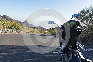 Motorcycle 125 parked in the roadside in a mountain road with curve. Naked motorbike from the behind in scenic asphalt and
