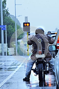 Motorcycle biker riding in rain in morning city traffic